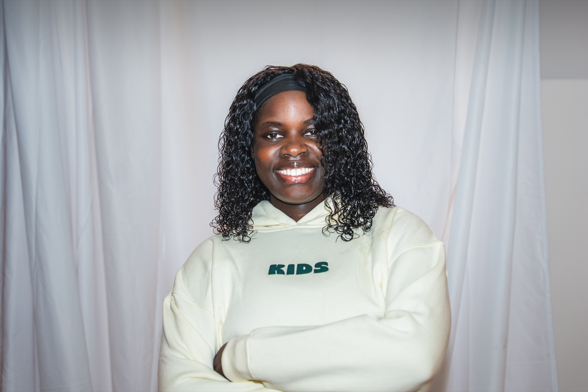 Julia smiling in the cream KIDS hoodie